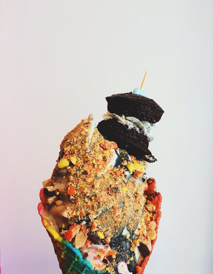 A vibrant ice cream cone stacked with colorful toppings and cookies, perfect for dessert lovers.