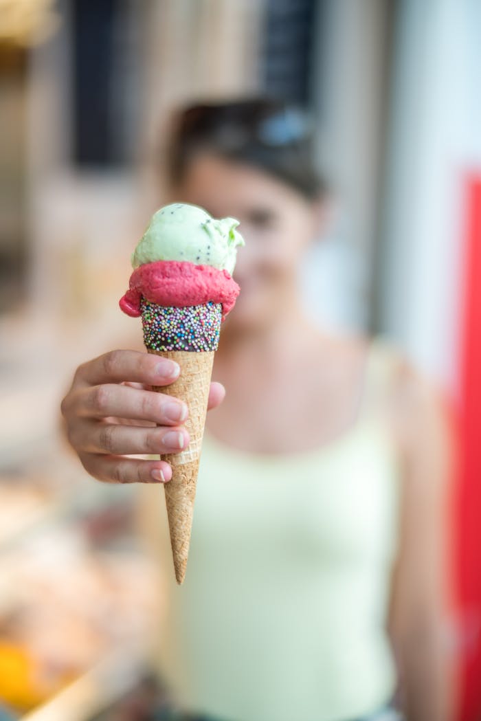 Woman holding a vibrant ice cream cone topped with sprinkles, creating a refreshing summer treat.